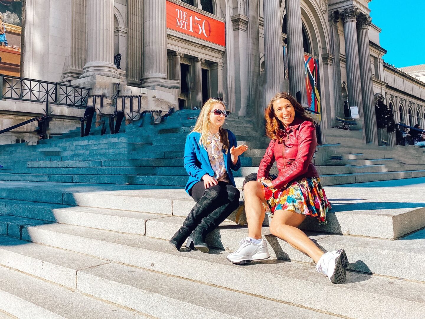 Two girls, dressed as Blair and Serena from Gossip Girl, sit on the Met Steps.
